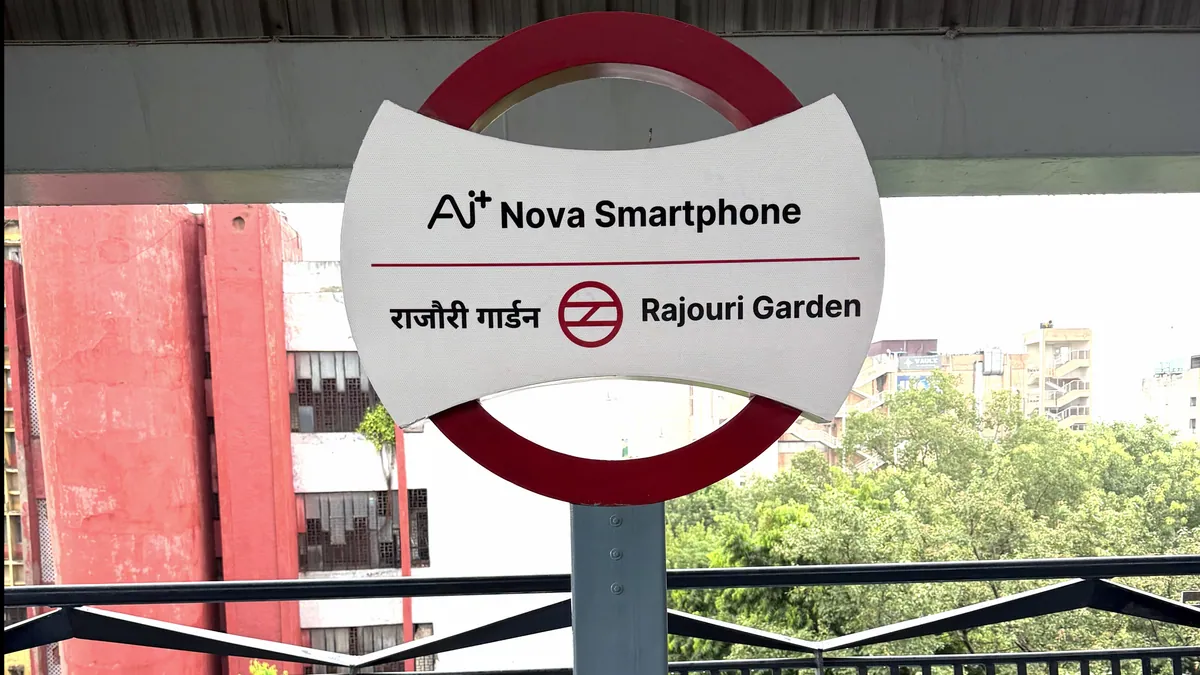 A Delhi Metro station sign reading Ai+ Nova Smartphone Rajouri Garden, in Ai+ Smartphone station branding