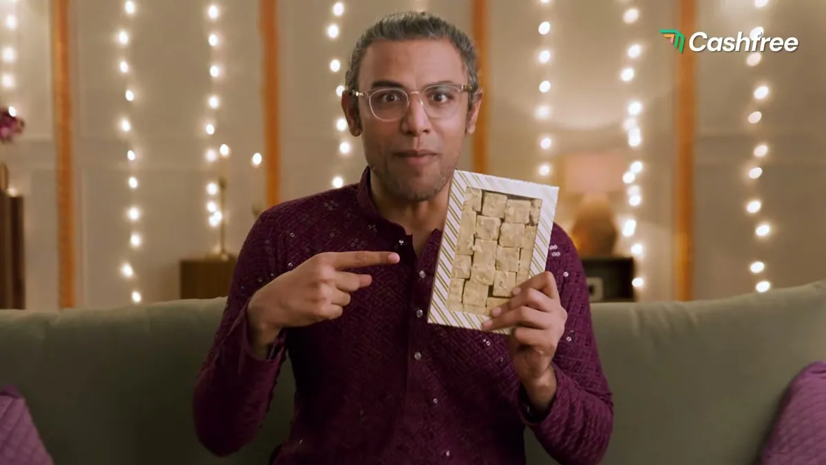Biswa Kalyan Rath holding a box of soan papdi in Cashfree's Mithai Joint Family film