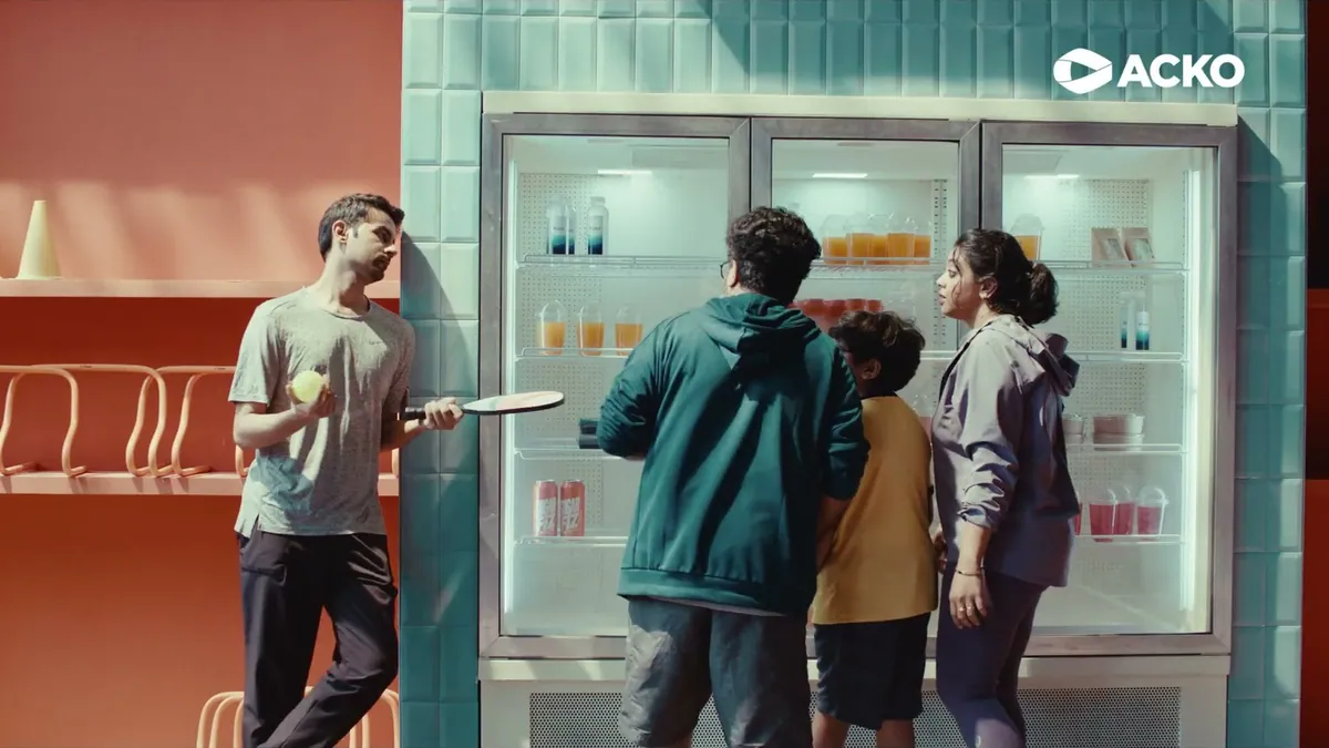 A frame from the ACKO Health Insurance film, a family standing in front of a fridge of energy drinks