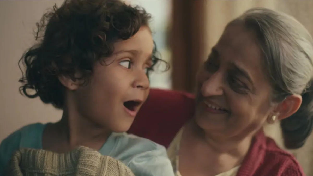 A child and an older woman laughing together, in a frame from the Stay Young at Heart campaign film