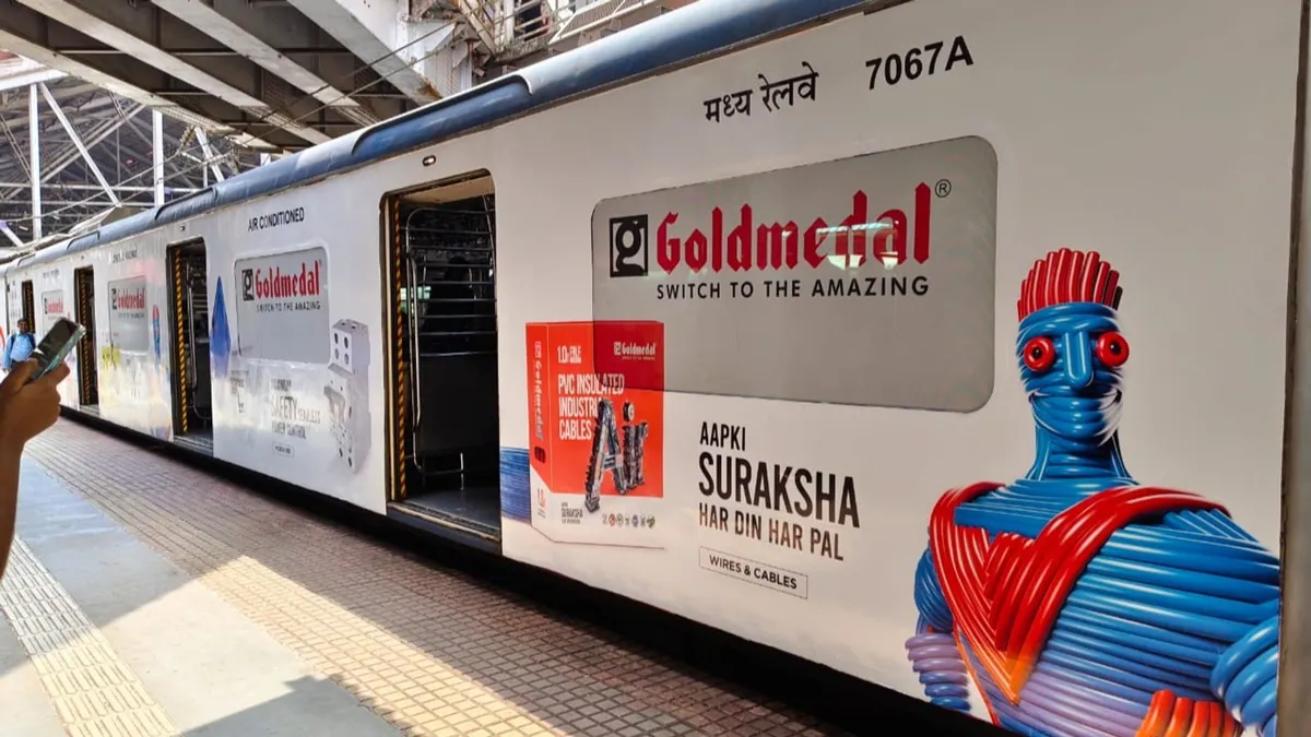 A Mumbai local train fully wrapped in Goldmedal Electricals branding at a suburban platform
