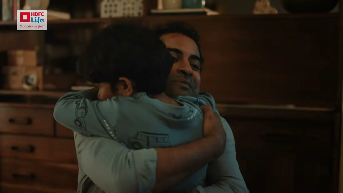 A frame from the HDFC Life term insurance film, a father holding his son after returning home