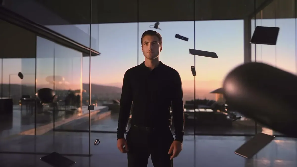 A man stands in a glass house at sunset as devices float around him, from Hyundai's BAYON name reveal film