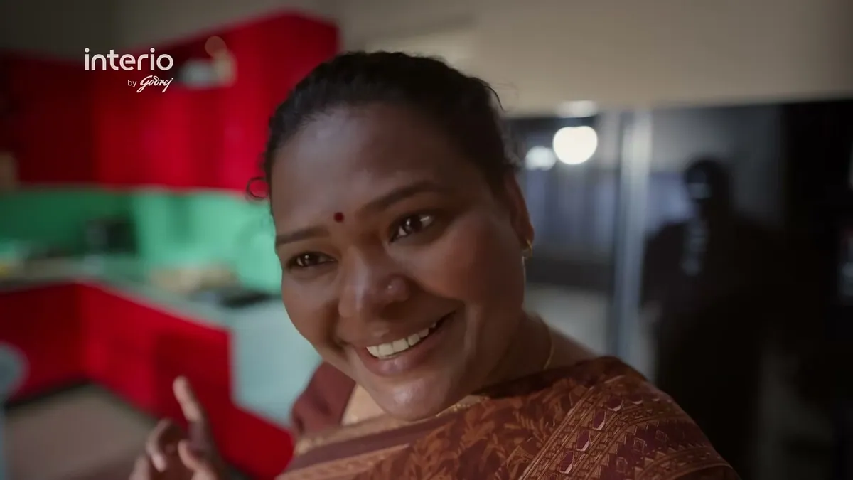A woman smiling in a red steel kitchen, a frame from the Interio by Godrej campaign film