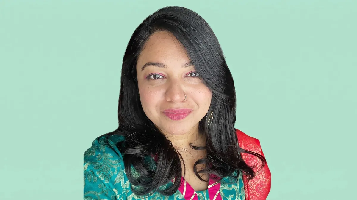 Portrait of Moumita Majumdar against a flat pastel mint backdrop