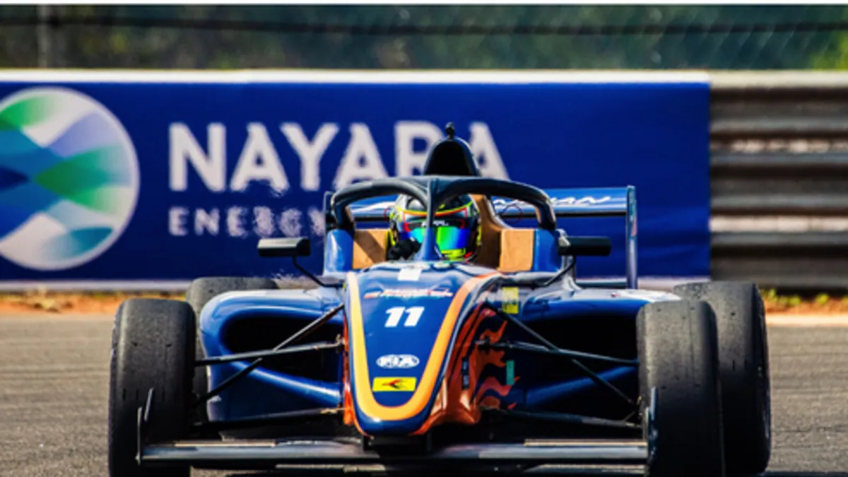 A Formula 4 car on track in front of Nayara Energy trackside branding at the Indian Racing Festival