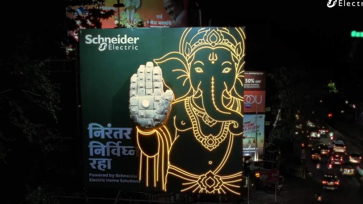 A lit Schneider Electric hoarding in Pune showing a Ganpati blessing hand built from light switches